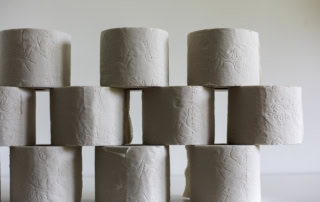 Toilet paper rolls sit stacked against a white background to showcase creping in tissue and towel products.